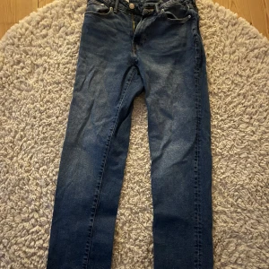 Blå straight jeans från H&M - Säljer ett par klassiska blå jeans från H&M med straight regular fit. Jeansen har fem fickor, normal passform och snygga kontrastsömmar. Perfekta för dig som gillar en enkel och tidlös stil.