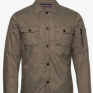 Brun overshirt från Snoot, M - Snoot Positano JKT är en brun overshirt med klassisk krage, svarta knappar och två bröstfickor Hör av er vid frågor eller egna bilder !. Jackan har lång ärm med dragkedjedetalj på ena ärmen och är tillverkad i lätt syntetmaterial. Perfekt för lager-på-lager och stilren look. Passar vid alla tillfällen.