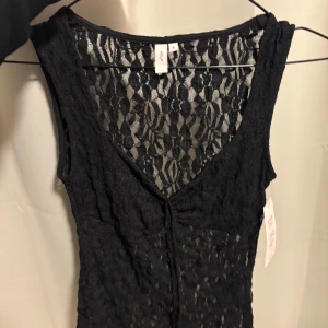 Spets topp - Supersnygg svart ärmlös spets topp från Nelly med v-ringning och transparent spets över hela klänningen. Figurnära passform och perfekt för dig som vill sticka ut med en elegant och trendig look. Toppen har fina spetsdetaljer och är riktigt stilren.