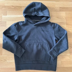 Mörkblå hoodie från Sail Racing  - Mörkblå hoodie från Sail Racing med broderad logga på bröstet och en stor känguruficka framtill. Tröjan har huva med snygg detalj och är tillverkad i mjuk bomullsmix. Perfekt för chill dagar eller när du vill ha en clean look.                        Storleken är för 14 år gammal/160