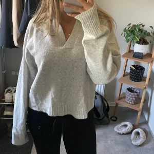 Ljusgrå stickad tröja med v-ringning - Säljer en supermysig ljusgrå stickad tröja med v-ringad hals.