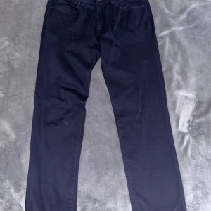 Mörkblå raka chinosbyxor - Snygga mörkblå chinosbyxor med klassisk femficksdesign och raka ben. Byxorna har en stilren look och passar perfekt till en avslappnad streetstyle. Materialet är mjukt och färgen är djup mörkblå. Storlek: 33/32. Köpt från Dressman. 