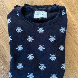 Svart tröja med bi-mönster från Gucci - Svart tröja från Gucci med unikt bi-mönster över hela plagget. Tröjan är tillverkad i 100% bomull och har rund halsringning samt långa ärmar. Perfekt för dig som vill sticka ut med en exklusiv och trendig look. . Tröjan är L men skulle säga att sitter mer som M. Vet ej om den är äkta eller inte då jag köpte den på plick av någon annan. om du har några funderingar är det bara att höra av sig🫡