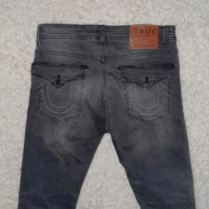 True religion jeans W32/L32 Chief Keef  - Snygga svarta jeans från True Religion med klassiska kontrastsömmar och ikoniska bakfickor med lock och knapp. Jeansen har en rak passform och är tillverkade i stretchig denim för extra komfort. Perfekta för dig som gillar streetwear och vill sticka ut.