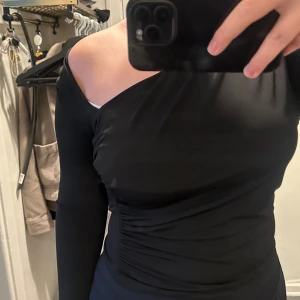 Svart oneshoulder topp  - Säljer en svart långärmad topp med oneshoulder-design och snygga rynkade detaljer. Jättefin men har aldrig kommit till användning💕Storlek M