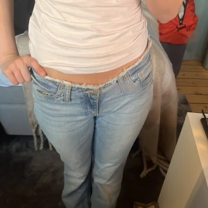 Ljusblå lågmidjade jeans  - Säljer ett par ljusblå jeans med låg midja och rå, fransad kant upptill. Jeansen har klassisk femficksdesign. Skitsnygga är tyvärr för stora för mig men älskar🥰