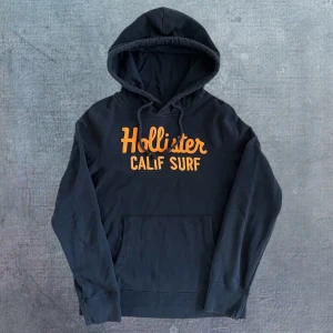 Hollister Hoodie - Säljer denna hoodien från Hollister, riktigt fin och i ett bra skick! Storlek L, kan även passa M, se mått. Längd: 66, bredd: 50, arm: 65. Skriv vid funderingar. Modellen är 183, 67kg.