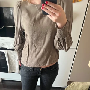 Grön blus med puffärmar - Säljer en grön blus med långa puffärmar och breda smockade muddar vid handlederna. Blusen har en rak passform och är tillverkad i ett tunt, mjukt tyg som ger ett luftigt intryck. Perfekt för dig som gillar stilrena och trendiga plagg. Hann inte stryka den💕