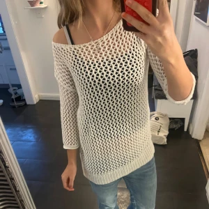 Vit stickad meshtröja med trekvartsärm - Säljer en vit stickad tröja med grovt meshmönster och trekvartsärmar. Tröjan har en avslappnad passform och är perfekt att slänga över ett linne eller bikini. Snygg offshoulder-look och ribbade muddar nedtill och vid ärmslut.🤍