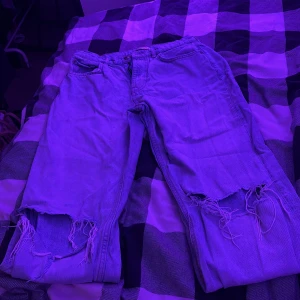 Ljusblå jeans från Gina perfect jeans - Säljer ett par ljusblå jeans från Gina perfect jeans i storlek 38. Modellen har klassisk femficksdesign och raka ben med stora slitningar och fransar vid knäna. Jeansen är tillverkade i jeansmaterial och har knapp och dragkedja framtill.