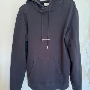 Saint laurent stl M - Svart hoodie från Saint Laurent i stl M passar dig som är mellan 175-185 cm. Tröjan är i bra skick, hör av dig vid minsta lilla  fundering och lägg gärna prisförslag!