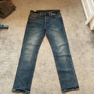 Levi's 501 blå jeans W31 L32 - Klassiska Levi's 501 jeans i blå tvätt. Jeansen har normal passform och är tillverkade i slitstarkt bomullsjeansmaterial. Snygga detaljer med nitar och knappgylf, samt den ikoniska läderpatchen bak i midjan.