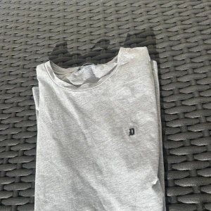 Dondup t-shirt  - Snygg grå t-shirt från Dondup i mjuk bomull. Klassisk rund hals och korta ärmar, med en liten broderad D-logga på bröstet. Perfekt basic att ha i garderoben, enkel att matcha med allt. Passar dig som gillar stilrena plagg med diskreta detaljer. 