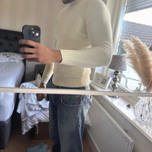 Vit stickad tröja från Ralph Lauren - Säljer en stilren vit stickad tröja från Ralph Lauren med den klassiska loggan broderad på bröstet. Tröjan har rund hals, ribbade muddar och är långärmad. Perfekt för dig som gillar clean och enkel stil. Denna e cremfärgad mer. Aldrig använd, pga att den e liten på mig