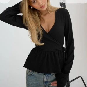 Svart omlottopp  - Säljer denna jättefina omlott toppen med långa ärmar och knytband i midjan. Den är i mycket bra skick.🫶Från Nelly!