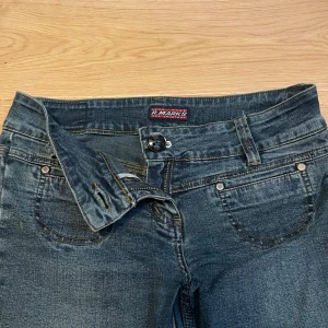 Blå bootcut jeans från R. Marks - Snygga blå jeans från R. Marks med klassisk femficksdesign och bootcut-ben. Jeansen har normal midja, dragkedja och knapp framtill samt detaljerade sömmar. Perfekta för dig som gillar en tidlös och avslappnad stil. 