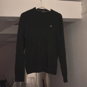 Svart merinoulltröja från Morris - Svart, klassisk tröja från Morris i 100% merinoull. Enkel design med rund hals och diskret Morris-logga på bröstet. Långärmad och perfekt för lager-på-lager under kyliga dagar.