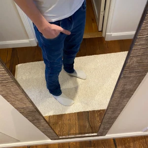 Replay Anbass Jeans - Säljer ett par blå Replay Hyperflex jeans med klassisk femficksdesign och snygga kontrastsömmar. Jeansen har slim passform och är tillverkade i stretchigt jeansmaterial för extra komfort. Märkespatch i läder baktill och diskret logga på fickan framtill.