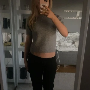 Grå croppad stickad topp - En jättefin stickad T-shirt som är i väldigt bra skick men som är lite nopprig. Säljer för 60 kr medan ordinarie priset är 400