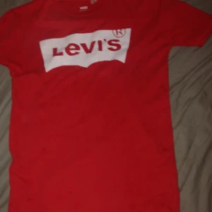Röd Levi's t-shirt med logga - Röd t-shirt från Levi's i storlek S med klassisk vit logga framtill. T-shirten har rund halsringning och korta ärmar. Tillverkad i mjuk bomull som är skön att ha på sig. Perfekt för en avslappnad och cool stil.