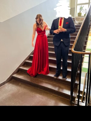 Röd balklänning med öppen rygg - Säljer nu min röda balklänning med smala axelband, fin v-ringning och mindre släp. Klänningen har öppen rygg med snörning som korsas och ger en elegant look. Perfekt för bal eller student! Sitter figurnära upptill och faller snyggt ner mot golvet. Nästan lång på mig som är 175 cm. På lappen står det storlek 0, men jag skulle säga att den är storlek 36-38. 