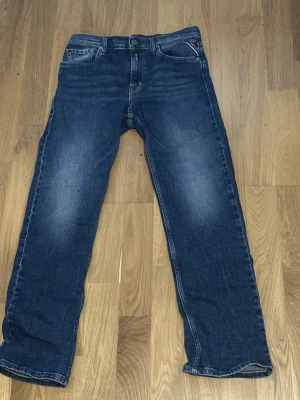 Blå jeans från Replay, slim fit - Säljer ett par klassiska blå jeans från Replay i rak passform. Jeansen har fem fickor, normal midja och snygga slitningar framtill för en avslappnad look. Tillverkade i tåligt denimtyg som passar perfekt till vardagsstilen.