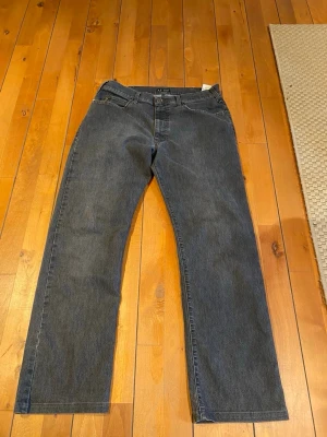 Mörkgrå Armani Jeans straight fit - Snygga mörkgrå jeans från Armani Jeans med klassisk femficksdesign och raka ben. Byxorna har metallknapp, dragkedja och logga på bakfickan. Materialet är slitstark jeansbomull och passformen är straight fit med normal midja. Size 36