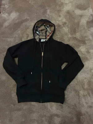 Burberry hoodie - Säljer min burberry hoodie. Den är storlek Small jag är ungefär 170cm och den är lite kort i armarna och den sitter precis vid midjan. Inga fel med den nästa helt ny bara testa på den 