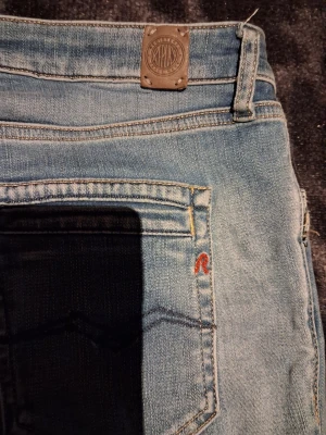 Ljusblå Replay jeans - Säljer ett par ljusblå jeans från Replay med klassisk femficksdesign och snygga slitningar. Jeansen har skinny passform och låg midja, med Replay-logga på bakfickan och framfickan. Materialet är mjukt jeans-tyg i bomull.