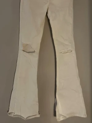 Bootcut vita jeans från g perfect jeans XS - Säljer ett par vita bootcut jeans från g perfect jeans i storlek XS. Byxorna har slitna hål vid knäna och är tillverkade i ett klassiskt jeansmaterial. Modellen har utsvängda ben och en fräsch, ljus ton som ger en cool vibe. Stretchiga!