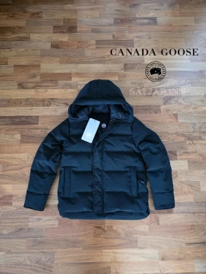 Canada Goose Macmillan Parka Black Label  - 🖤 Canada Goose Macmillan Parka Black Label 🖤 Exklusiv och mycket varm vinterjacka från Canada Goose i Black Label-utförande med svart emblem och stilren premiumdesign. Helt ny med tagg kvar.. Perfect för nordiskt klimat med tjock dunfyllning, skyddande huva och djupa dragkedjefickor. En lyxig och praktisk vinterfavorit.  📦 Snabb leverans – skickas samma dag 📩 Skriv vid intresse