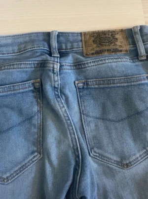 lågmidjade jeans - Säljer ett par ljusblå bootcut jeans från Crocker med klassisk femficksdesign, uppsprättade nertill