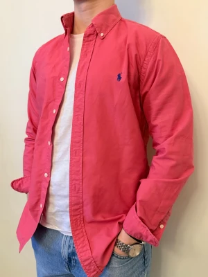 Rosa Ralph Lauren skjorta - Nu säljer vi ännu en snygg polo skjorta som passar till alla tillställningar! Du ska kunna uttrycka stil utan att det kostar för mycket!🕺💼🤩  Storlek👔: M Nypris💰:  ca 1399 kr