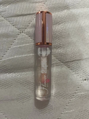 Karite Flower 24K magic Läppglans - En magic Transparent läppglans med guldglitter och en liten blomma inuti, från Karite. Snyggt hylsa med roséguld och ljusrosa detaljer som glittrar. Perfekt för att ge läpparna extra glans och en touch av lyx.