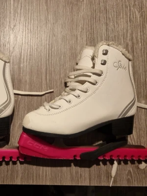 Skridskor. - Snygga vita skridskor från Spin med mjuk fuskpäls runt kanten och klassisk snörning. Använda en säsong på skolan Kommer med rosa skydden.