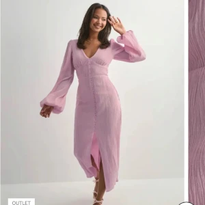 Ljusrosa långklänning Nelly - Superfin långklänning i rosa med v-ringning och långa puffärmar. Klänningen har knappar framtill och en slits som ger en snygg touch. Tillverkad i ett lätt, strukturerat material som känns luftigt och bekvämt. Perfekt för vår och sommar! Köpt på nelly för nypris på 799kr + frakt. Endast prövad