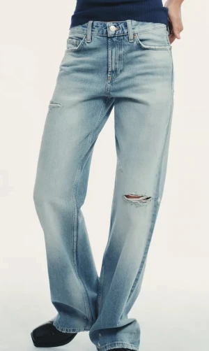 Ljusblå ripped jeans med loose fit - Snygga ljusblå jeans med slitna detaljer och hål på benen. Modellen har en loose fit och raka ben, perfekt för en avslappnad look. Passar 38-40.