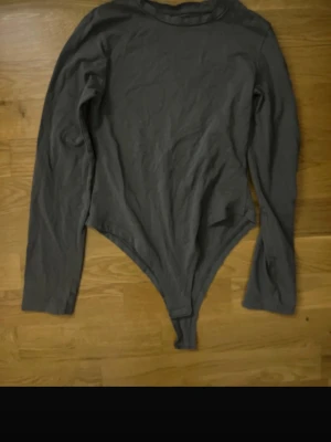 Mörkgrön långärmad body från Primark - En enkel mörkgrön långärmad body från Primark i stretchigt material. Modellen har rund halsringning och är figurnära med klassisk knäppning nedtill. Perfekt att styla med jeans eller kjol för en clean look.