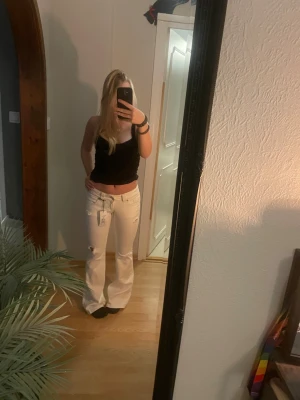 Vita lågmidjade jeans i trendig passform - Snygga vita lågmidjade jeans i en modern, lätt utsvängd modell. Väldigt smickrande passform som sitter bra över höfter och faller rakt/bootcut nedåt benen. Perfekta för både vardag och fest – enkla att styla med linne, crop top eller oversized skjorta. Från Gina men är helt slutsålda. Nysläppta!!  Jeansen har diskreta slitningar som ger en avslappnad men stilren look. Klassiska bakfickor med snygg sömdetalj. Använda fåtal gånger och i fint skick. Helt nya!!   ✔ Låg midja ✔ Trendig passform 