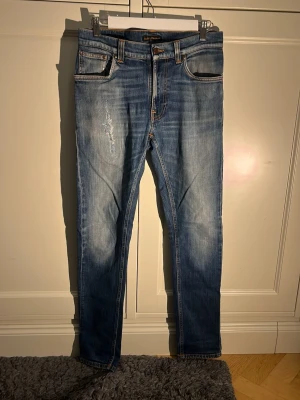 Nudie jeans  - Säljer ett par blå jeans från Nudie i str W30 L32. De har en snygg lagning på ena låret och en snygg tvätt. I modellen sitter de slim