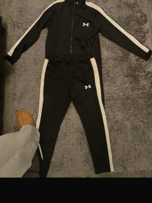 Svart under armour tracksuit  - Svart och vit randig under armour tracksuit perfekt till storlek M