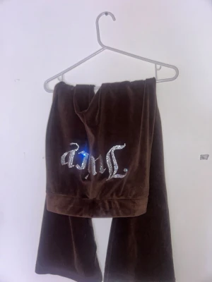 Bruna velourbyxor Juicy Couture S - Säljer ett par bruna velourbyxor från Juicy Couture i storlek S. Byxorna har  glittriga strasstenar som bildar Juicy-loggan på baksidan. Mjukt material och klassisk 00-talsstil.