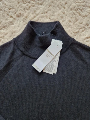 Svart långärmad klänning i merinoull Lindex polo - Mysig svart långärmad klänning från Lindex i mjuk merinoull. Modellen är rak med polokrage och ribbade muddar vid ärmslut. Perfekt för dig som gillar stilren och enkel design med premiumkänsla.