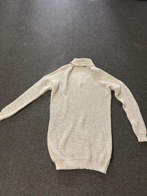 Beige stickad polotröja - Säljer en beige stickad polotröja med v-ringning. Tröjan har lång ärm och är ribbstickad för en snygg och enkel look. Perfekt för lager-på-lager och passar till allt från jeans till kjol.