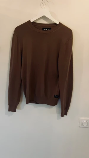 Beige stickad tröja från Replay XS/S - Snygg beige stickad tröja från Replay med rund hals och ribbade muddar vid ärmslut och nederkant. Tröjan har en stilren look och en diskret Replay-logga nedtill. Perfekt för dig som gillar enkel och clean stil.