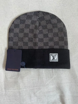 Louis Vuitton svart och grå mössa - Snygg mössa från Louis Vuitton i svart och grått med klassiskt rutmönster och uppvikt kant. LV-logga i vitt och svart framtill. Stickad i mjukt material som håller dig varm och stilren. Perfekt accessoar för dig som gillar exklusiva märken.