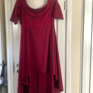 Röd off shoulder långklänning med spetsdetaljer - Säljer en elegant röd långklänning med vacker spets upptill och korta ärmar. Klänningen har en mjuk, flytande kjol och en v-ringning. Storlek xl, 46. 