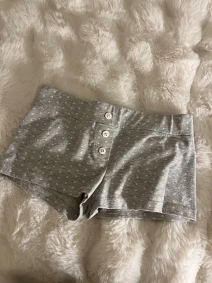 shorts med knappar -  säljer ett par gråa pyjamas shorts med knappar från Gina Tricot. De är jättefina och har små stjärnor på sig. Jag har använt dem ett par gånger men inga slitningar eller tecken på att de är väl använda. De är i storlek 146-152. Skriv om ni har frågor. 