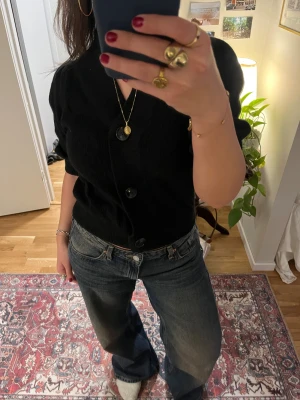 Svart kofta från Neo Noir med puffärm - Svart kofta från Neo Noir med puffiga korta ärmar och bred ribbad krage. Koftan har stora svarta knappar framtill.