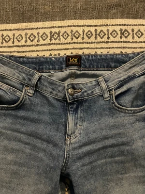 Lowwaisted jeans från Lee - Säljer par snygga och stretchiga jeans från Lee. Jeansen har en låg midja och ljusblåa ”slitningar”. 